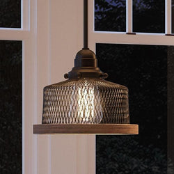 A unique lighting fixture, the Urban Ambiance UHP2731 Vintage Pendant Light with an Olde Bronze Finish from the Eugene Collection hangs over a window in a living room.