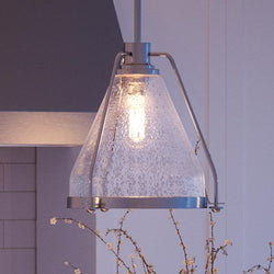 A beautiful pendant light from the Rochdale Collection, specifically the UHP2990 Industrial Pendant Light with a glass shade, is hanging over a fireplace.