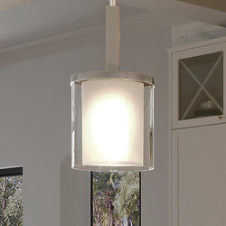 A unique pendant lamp, UHP3200 Contemporary Pendant Light, hangs over a window in a kitchen with a brushed nickel finish from the Evanston Collection by Urban Ambiance.
