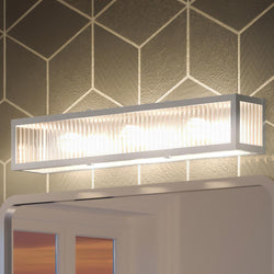 A bathroom with a unique lighting fixture: the UHP3590 Minimalist Bath Vanity Light from the Bismarck Collection by Urban Ambiance, complemented by a mirror.