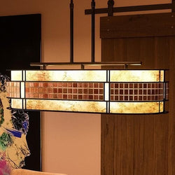 A unique Art Deco linear chandelier, 21"H x 37"W, with a Copper Revival Finish from the Genoa Collection hanging over a living room.