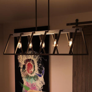 A unique lighting fixture, the UQL2811 Industrial Chandelier from the Bergen Collection by Urban Ambiance adds a gorgeous touch to a room with a painting on the wall.