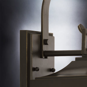 Close-up of the Urban Ambiance UHP1192 Colonial Outdoor Wall Light from the Calderdale Collection, measuring 15-1/8″ x 5-1/2″, featuring an arched arm and rectangular backplate in an Olde Bronze finish with clear beveled glass, mounted against a gradient background.