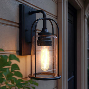 The Urban Ambiance UHP1300 Farmhouse Outdoor Wall Sconce from the Henderson Collection features a midnight black finish and clear glass shade, illuminating your entryway with charm and style. Measures 12.75''H x 6.125''W.