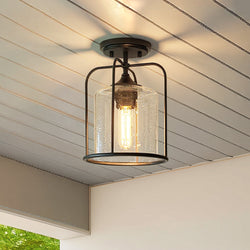 The Urban Ambiance UHP1305 Farmhouse Outdoor Ceiling Light from the Henderson Collection features a midnight black finish and clear seeded glass, and is mounted to a white, paneled ceiling.