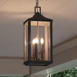 The Urban Ambiance UHP1401 Calderdale Farmhouse Outdoor Pendant, 23.75''H x 9.5''W in midnight black, features a rectangular metal frame with beveled glass and three candle-style bulbs, perfect for covered porch ceilings.