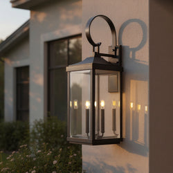 The Urban Ambiance UHP1404 Calderdale Collection Transitional Outdoor Wall Sconce, 30.625''H x 9.5''W in Midnight Black, is mounted on a light-colored exterior wall, casting elegant shadows and illuminating the area at dusk.