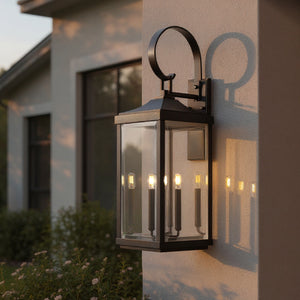 The Urban Ambiance UHP1404 Calderdale Collection Transitional Outdoor Wall Sconce, 30.625''H x 9.5''W in Midnight Black, is mounted on a light-colored exterior wall, casting elegant shadows and illuminating the area at dusk.