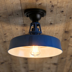 The Urban Ambiance UHP1498 Industrial Outdoor Ceiling Light from the Gary Collection features a navy finish and industrial design, measuring 9-1/2"H x 13-1/4"W x 13-1/4"D, and is mounted on a wooden plank ceiling with an exposed bulb.