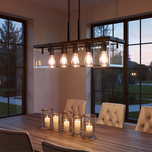 A modern dining room showcases the Urban Ambiance UHP2440 Modern Farmhouse Chandelier in Olde Bronze from the Bristol Collection above a wooden table with six cushioned chairs and five candles in glass holders.