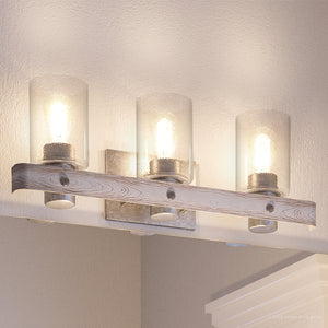 The UHP2485 Modern Farmhouse Bath Fixture from Urban Ambiance’s Adelaide Collection features a galvanized steel finish and clear glass shades, perfect for rustic lighting above a mirror on a textured wall.