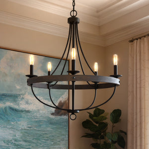 The Urban Ambiance UHP2901 Farmhouse Chandelier from the Adelaide Collection, featuring a 30" x 26" charcoal finish and five exposed bulbs, hangs in a room with ocean wave art, light walls, and a potted plant.