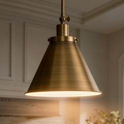 The UHP4006 Traditional Pendant from the Pawtucket Collection by Urban Ambiance, featuring an Olde Brass finish and measuring 12.75''H x 12.25''W, hangs illuminated in a modern interior space, casting a warm glow from the ceiling.
