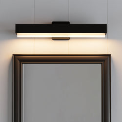 The UHP4841 Scandinavian Indoor Bath Light from Urban Ambiance’s Flensburg Collection—measuring 4-13/16″H x 3″W x 24″D in a matte black finish—is mounted above a framed mirror on a light-colored wall, casting a soft downward glow that’s perfect for modern bathroom lighting.