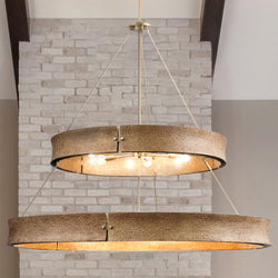 The UHP5033 XXL Modern Rustic Indoor Chandelier by Urban Ambiance (42''H x 48''W, Soft Gold) from the Richmond Collection features exposed bulbs and hangs from the ceiling against a light brick wall for a striking industrial look.