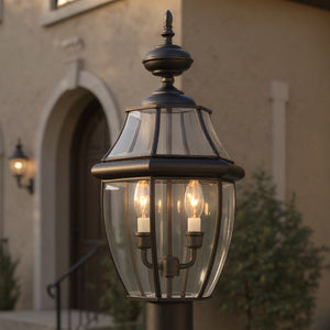 Close-up of the Urban Ambiance UQL1148 Colonial Outdoor Post Light from the Cambridge Collection, 21"H x 11"W in Black Silk finish, featuring beveled glass and three bulbs, shown in front of a house with an arched entry and wooden door.