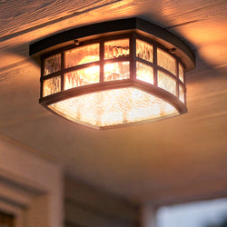 A close-up of the Urban Ambiance UQL1248 Craftsman Outdoor Ceiling Light from the Zurich Collection, featuring a black silk finish and marine-grade construction, installed on a wooden ceiling.