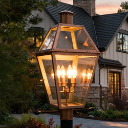 The Urban Ambiance UQL1373 Historic Outdoor Post/Pier Light, 26"H x 17"W in Rustic Copper from the Paris Collection glows at dusk, elegantly illuminating landscaping with handcrafted style.
