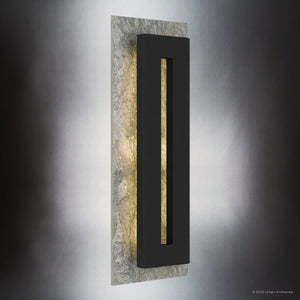 The UQL1881 Luxe Industrial Outdoor Wall Sconce by Urban Ambiance features a minimalist Earth Black finish, marine-grade construction, and a rectangular design with a vertical cutout and stone-like back, softly lit by an integrated LED from behind.