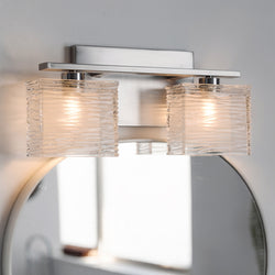 The Urban Ambiance UQL2720 Modern Bathroom Light from the San Diego Collection features two square, sandblasted glass shades and a sleek brushed nickel finish, measuring 6.75"H x 15"W, elegantly mounted above a mirror on a white wall.