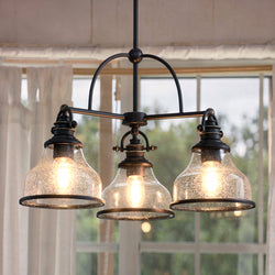 The Urban Ambiance UQL3666 Pasadena Collection Traditional Chandelier (15.5''H x 24''W, Parisian Bronze Finish) features three lights with clear glass dome shades and exposed bulbs, perfect for indoor spaces with white curtains.