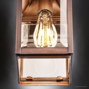 Close-up of a lit UFS1000 Transitional Outdoor Wall Sconce (15''H x 5.5''W, Genuine Copper, Dark-Patina) from the Calderdale Collection by Urban Ambiance, showing its vintage-style bulb and beveled glass photographed from below.