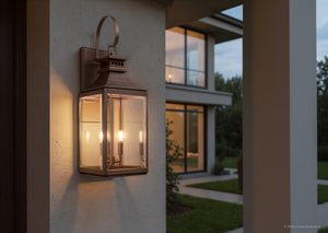 The Urban Ambiance UFS1002 Calderdale Collection transitional outdoor wall sconce in genuine copper and dark-patina is mounted on a modern home’s exterior, softly illuminating the entrance at dusk.