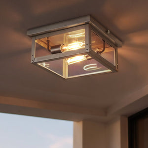 A square ceiling light fixture from the Darwin Collection by Urban Ambiance, featuring a glass and stainless steel finish and exposed bulbs, is mounted on a beige ceiling and illuminates the surrounding area.