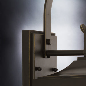 Close-up of the UHP1194 Colonial Outdoor Wall Light from the Calderdale Collection by Urban Ambiance, showcasing a graceful curved arm and decorative detailing in an elegant Olde Bronze finish with beveled glass panes, set against a neutral background. Dimensions: 30-5/8″ x 9-1/2″.