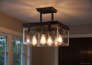The Urban Ambiance UHP2448 Modern Farmhouse Ceiling Fixture from the Bristol Collection, featuring a square 16-3/4″ wide Olde Bronze metal frame, six exposed light bulbs, and beveled glass sides, is mounted on a white ceiling in a room with large windows.