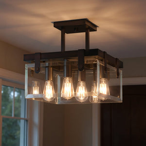 A rectangular, semi-flush ceiling fixture from the Bristol Collection by Urban Ambiance, featuring an Olde Bronze finish and exposed bulbs, hangs from a white ceiling in a room with tan walls and windows. This Modern Farmhouse piece (UHP2448) measures 14 inches high by 16-3/4 inches wide.