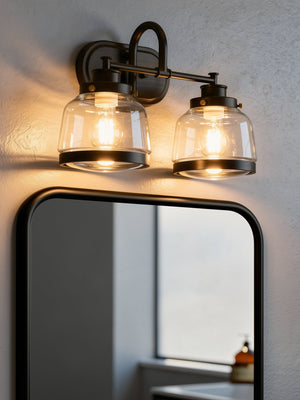 The Urban Ambiance UHP2537 Luxe Industrial Bathroom Vanity Light from the Nottingham Collection, featuring an Olde Bronze finish and clear glass shades, is mounted above a rectangular mirror on a light-colored wall.