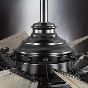 Close-up of the Urban Ambiance Saybrook Collection's UHP9478 Tuscan Indoor Ceiling Fan with a matte black central fixture and light wood blades, featuring a windmill-inspired design, partially visible. Dimensions: 26-1/4''H x 60