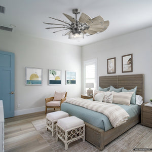 A bedroom featuring a wooden bed from the Saybrook collection, light blue bedding, two stools at the foot, a chair, and framed artwork adorns the walls. The rustic design is completed by an Urban Ambiance UHP9481 Tuscan Indoor Ceiling Fan with a unique blade design in Antique Nickel.