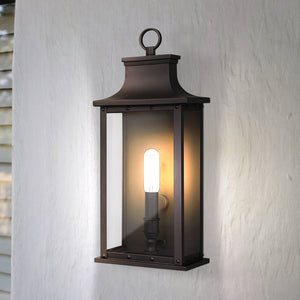 The Urban Ambiance UQL1721 Halle Collection Classic Outdoor Wall Sconce, with beveled glass panels and an old bronze finish, is mounted on a white textured wall.