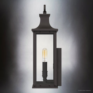 The UQL1721 Classic Outdoor Wall Sconce by Urban Ambiance features a rectangular design, old bronze finish, beveled glass panels, and visible vertical bulb. Size: 15.50''H x 6.50''W x 5.50''D. From the Halle Collection with marine-grade durability.
