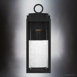The Urban Ambiance UQL1780 Classic Outdoor Wall Sconce from the Nicosia Collection features a matte black marine-grade rectangular frame with seeded glass and a circular top ring. Size: 18.75''H x 7''W x 7.75''D.