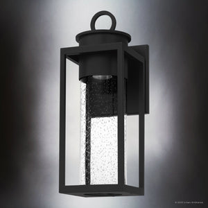 The UQL1780 Classic Outdoor Wall Sconce by Urban Ambiance features a matte black, marine-grade frame in the Nicosia Collection (18.75''H x 7''W x 7.75''D), mounted on a wall with a soft gradient light in the background.