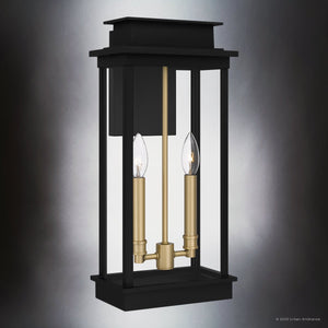 The Urban Ambiance UQL1821 Selby Collection outdoor wall sconce features marine-grade construction, a matte black finish, and gold interior accents for a modern lantern look with two exposed candle-style bulbs. Size: 18.75''H x 8.75''W x 6.00''D.