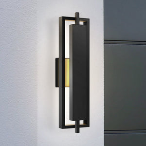 The Urban Ambiance UQL1840 Modern Outdoor Wall Sconce from the Juniper Collection features a matte black, rectangular frame and marine-grade construction. It is mounted on a white wall next to gray panels. Size: 20.50''H x 5.75''W x 3.75''D.