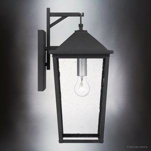 The Urban Ambiance UQL1871 Elmwood Collection outdoor wall sconce features a mottled black finish, marine-grade construction, clear glass enclosure, and visible bulb. Size: 19.75''H x 9.25''W x 11.00''D.