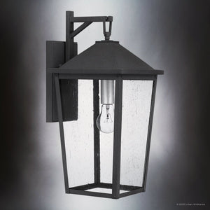 The Urban Ambiance UQL1871 Modern Rustic Outdoor Wall Sconce from the Elmwood Collection features a mottled black finish and seeded glass, showcasing a visible bulb. Sized at 19.75''H x 9.25''W, it's designed for marine-grade durability on gray walls.
