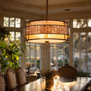An Urban Ambiance UQL2431 Art Deco Deco Chandelier from the Genoa Collection, featuring a rich Copper Revival finish and a 16-inch round design, hangs above a dining table adorned with a plant centerpiece in a sunlit room with large windows.