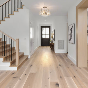 Modern hallway with light wood floors, white walls, a staircase with black railings on the left, a black door at the far end, and the Urban Ambiance UQL3310 Utilitarian Ceiling Light from the Clearwater Collection (12″H x 16″W) in a brushed nickel finish.