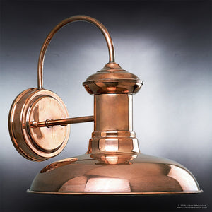 The UHP1023 Luxe Industrial Outdoor Wall Light from Urban Ambiance’s Palermo Collection features a solid copper finish, a gracefully curved arm, and a round base. Measuring 10.75 inches high by 10 inches wide and set against a subtle gray gradient background, this piece adds an elegant vintage charm to any exterior space.