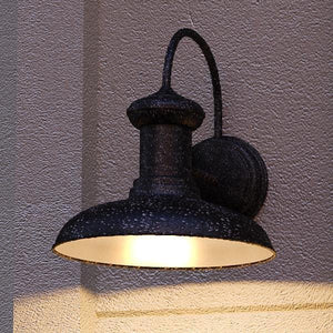 An UHP1029 Industrial Chic Outdoor Wall Light, 12.25"H x 12"W, with a unique Olde Iron Finish by Urban Ambiance on the side of a building.
