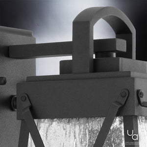 Close-up of the UHP1053 English Country Outdoor Wall Light from the Saint Paul Collection by Urban Ambiance, featuring a midnight black finish, curved handle, and textured glass panel that blends English-inspired lighting details. The Urban Ambiance logo appears in the lower right corner.