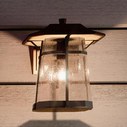 A beautiful and unique Urban Ambiance UHP1070 Rustic Outdoor Wall Light in Coffee Bronze Finish, part of the Gold Coast Collection, illuminates the side of a house.