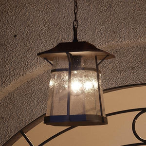 An UHP1074 Rustic Outdoor Pendant Light, 12.375"H x 8.5"W, Coffee Bronze Finish, Gold Coast Collection hanging from a doorway in a unique and beautiful manner