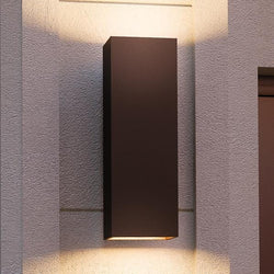 An UHP1110 Minimalist Outdoor Wall Light, 18"H x 6"W, Olde Bronze Finish, Madrid Collection by Urban Ambiance on the side of a building. (luxury